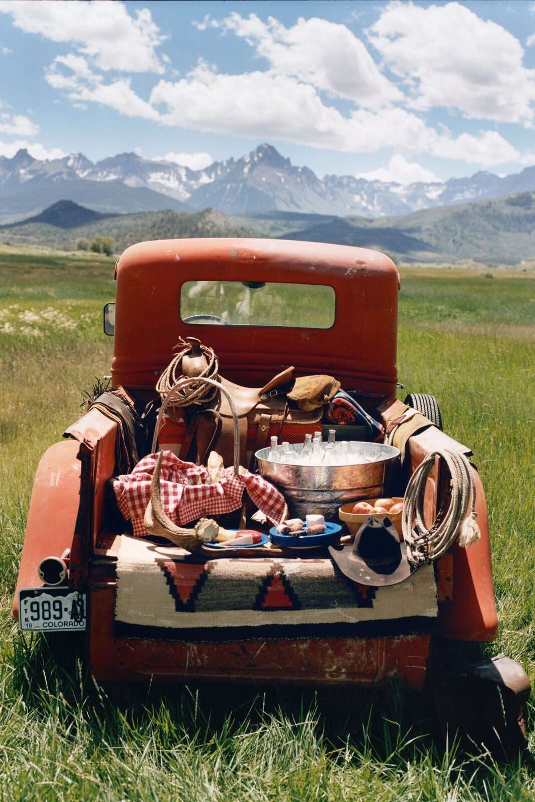 Vintage pickup truck tailgate laid out with drinks and bread in a field