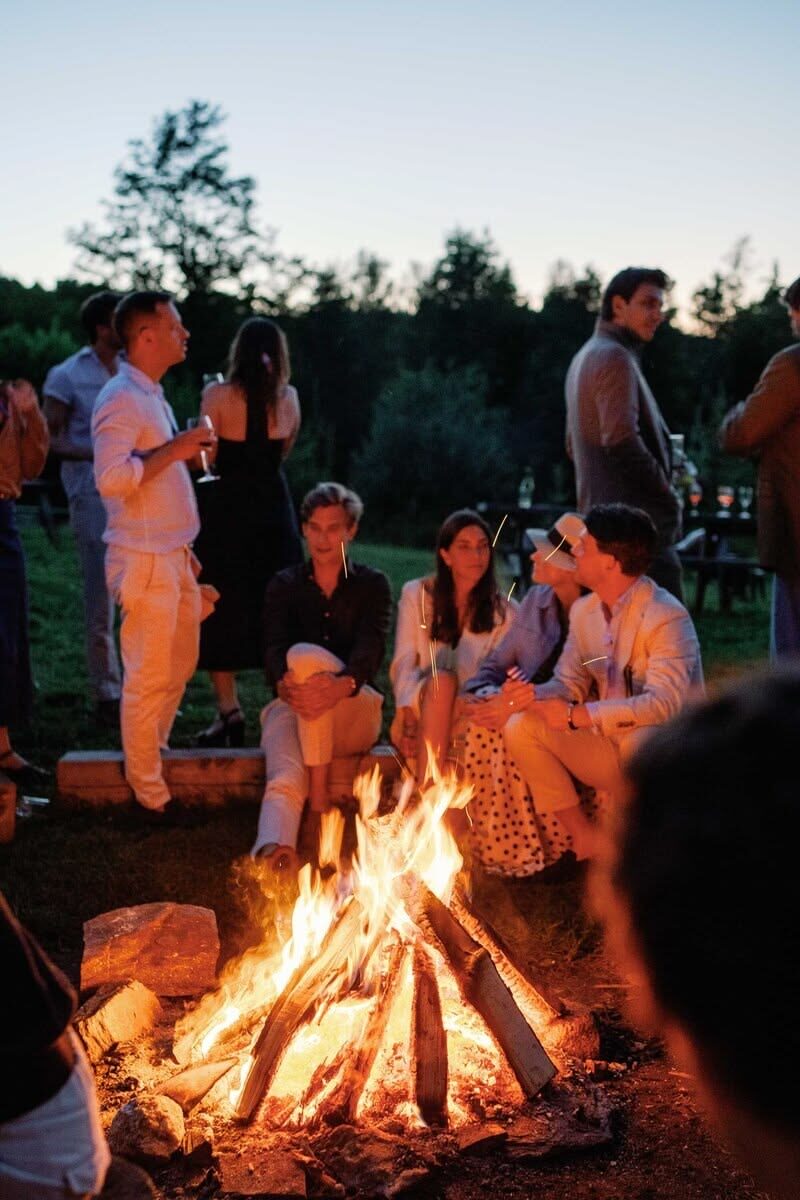 Guests gathered around a bonfire at dusk