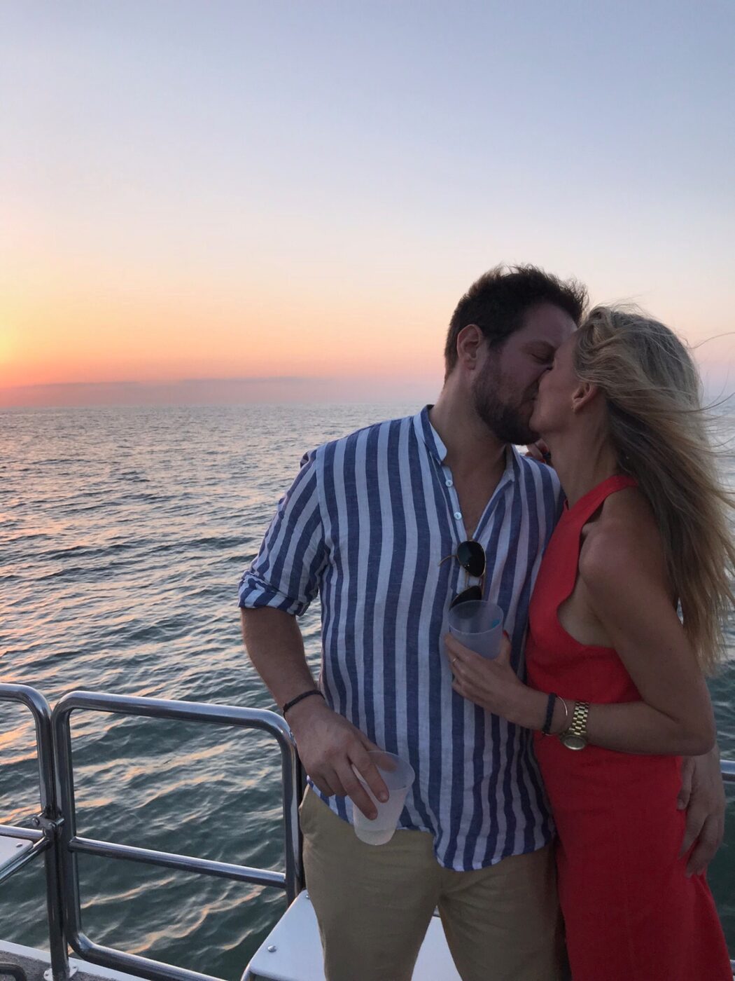 Phoebe and Chris kissing on a boat at sunset